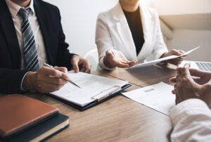 Pessoas em reunião analisando documentos sobre uma mesa de madeira